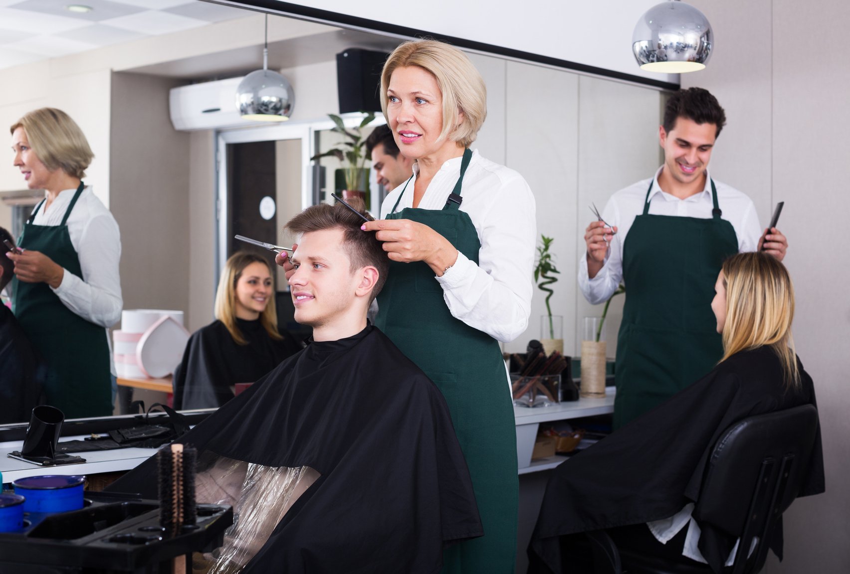 Senior hairdresser serving teenager